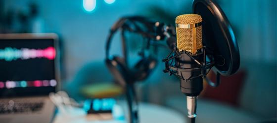 immagine sfuocata di uno studio di registrazione con microfono e cuffie in primo piano