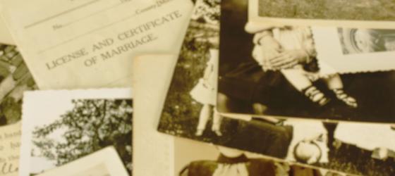 una serie di foto antiche sparse sul tavolo con un vecchio certificato di matrimonio