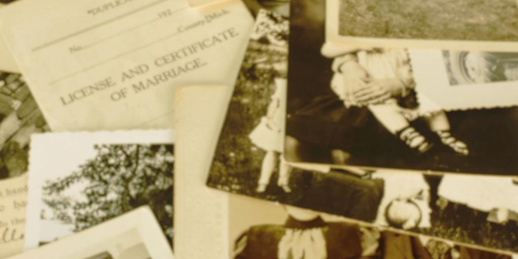 una serie di foto antiche sparse sul tavolo con un vecchio certificato di matrimonio